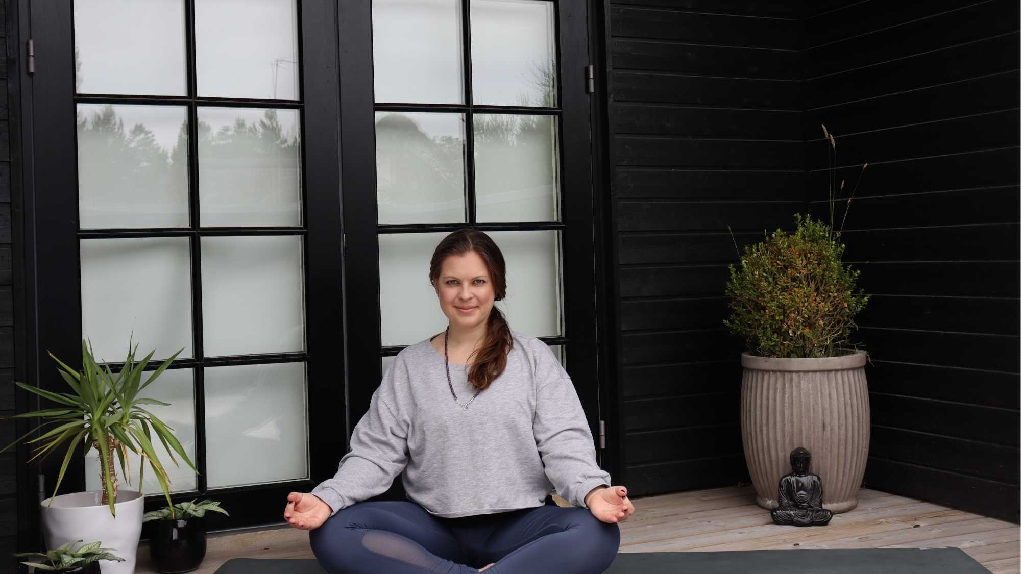 Das Bild zeigt eine Frau, die auf einer Yogamatte meditiert.