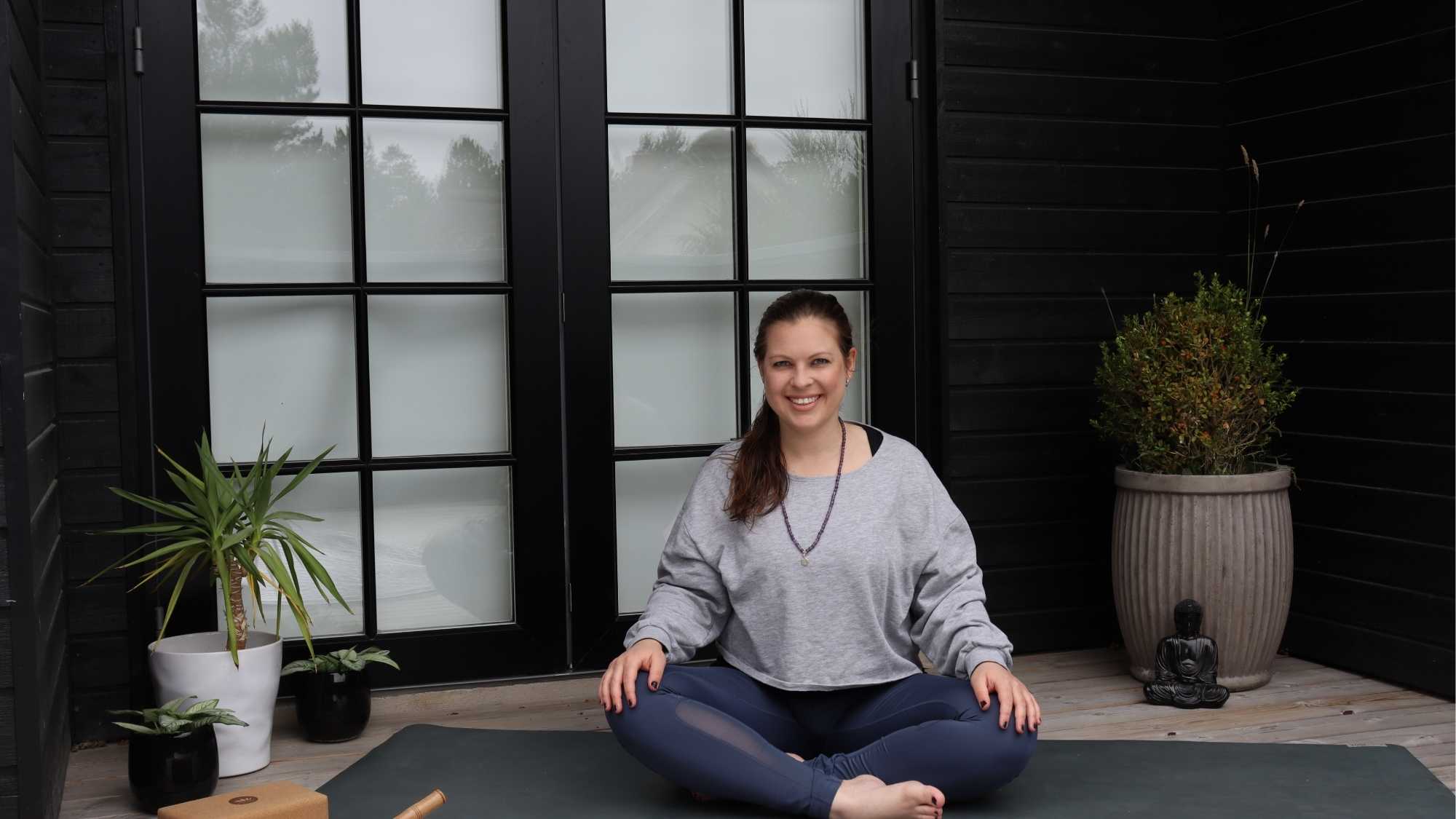 Eine Frau sitzt auf einer Yogamatte im Yogasitz.